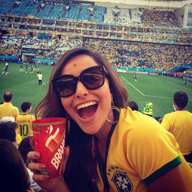 Foto em que é possível ver uma famosa apresentadora de TV segurando o copo da marca citada abaixo, durante partida da Copa do Mundo 2014.