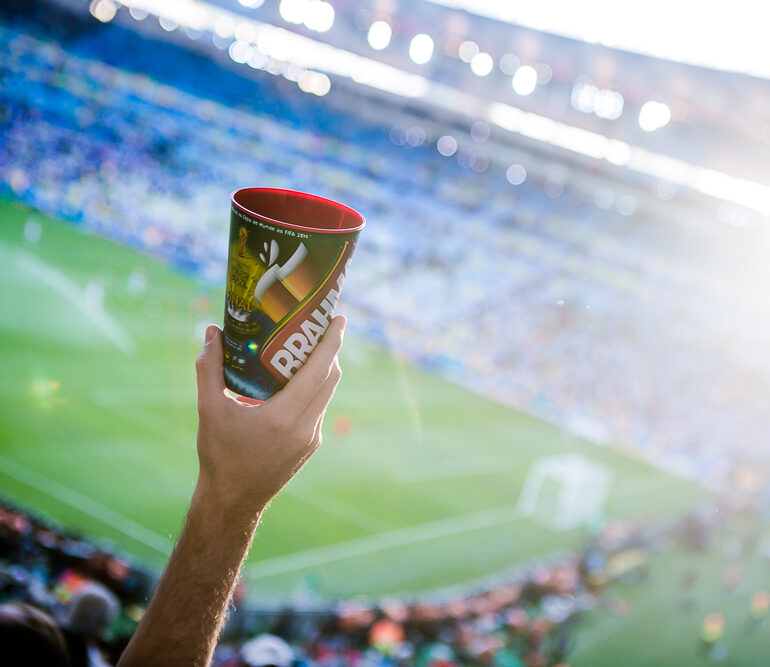 Copo Brahma na mão de um torcedor, arquibancada de partida de futebol - Copa 2014